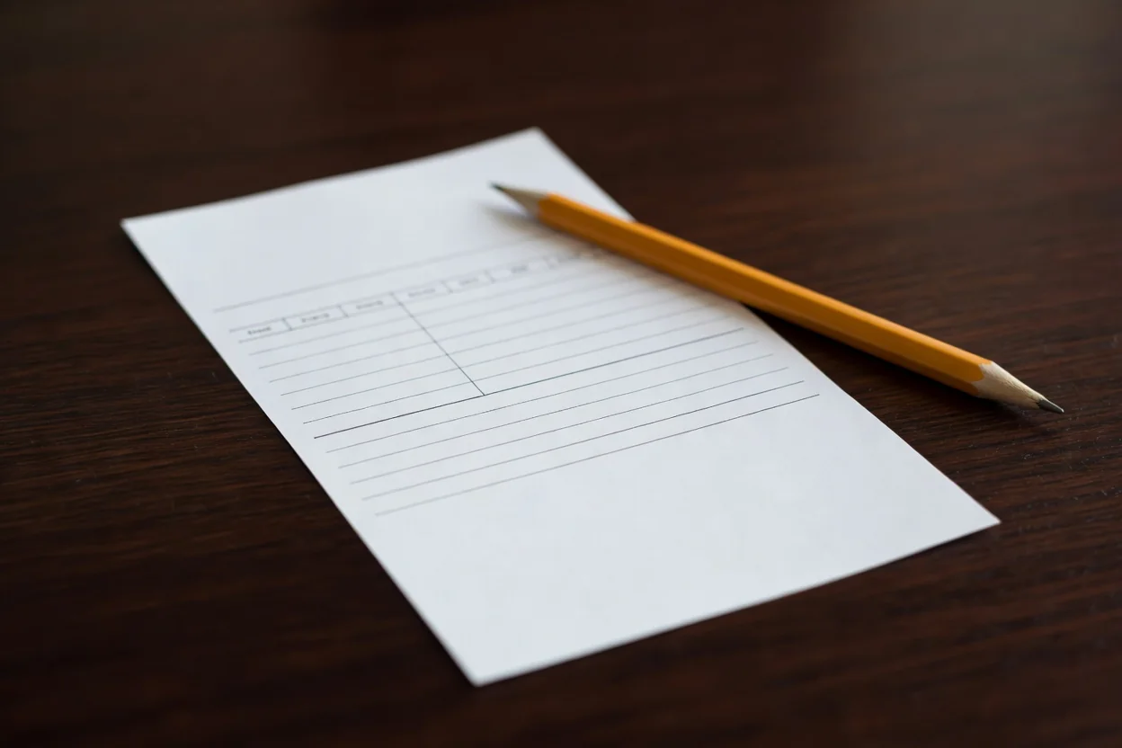 Paper betting slip and pencil resting on a dark desk